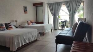 A room with two beds, a sofa, a ceiling fan, and a window with curtains. - Beach Front Flat!! (Cancún)