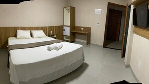 A bedroom with a bed, a desk, a mirror, and a television. - Garcia Palace Hotel (Marabá)