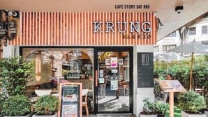 Un café appelé « KRUNG », doté d’un design moderne, d’une terrasse et d’une enseigne indiquant « JOUR 660 DE L’HISTOIRE DU CAFÉ ».