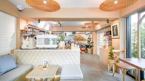 Un café chaleureux avec un comptoir, un espace salon et une cuisine en arrière-plan.