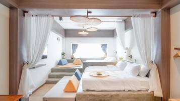 A modern bedroom with a bed, a small seating area, and a window.