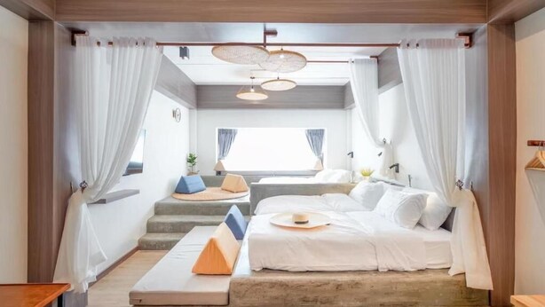 Une chambre moderne avec un grand lit, un petit coin salon et une vue sur l’extérieur.