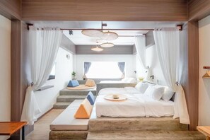 Un dormitorio moderno con una cama grande, un pequeño rincón de descanso y vistas al exterior.