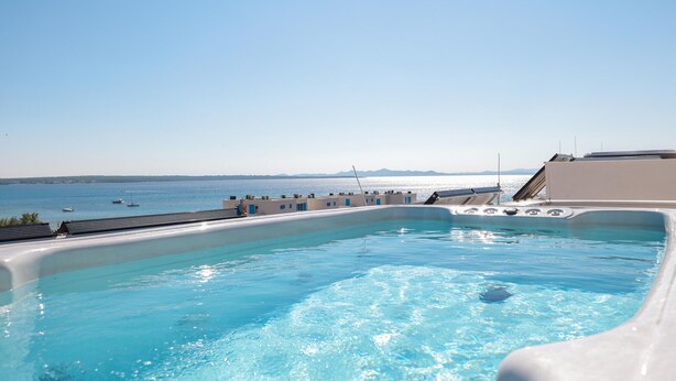 A swimming pool with a view of the sea and distant mountains.