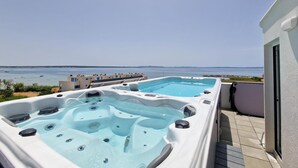 A rooftop with two hot tubs overlooking a body of water.