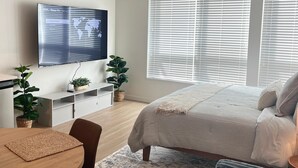 Une chambre moderne avec un grand lit, un téléviseur fixé au mur, une table à manger et un canapé.