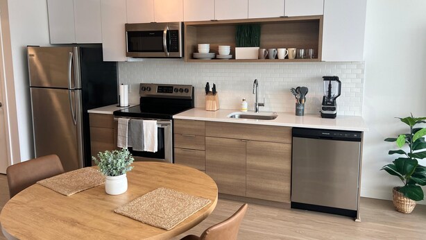 Une cuisine moderne dotée d’appareils électroménagers en acier inoxydable, de meubles en bois et d’un îlot central avec des sièges.