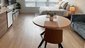 Un appartement moderne comprenant un coin repas, un canapé, une tél évision et une fenêtre avec des stores.