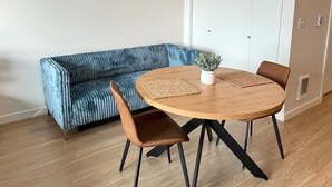 Un salon moderne avec une table ronde en bois, deux fauteuils marron, un canapé bleu et une plante en pot.