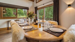 A dining table set for six with a vase of flowers, wine bottles, and candles. - 7BR Luxury Chalet with Hammam, Cinema, gym and Mont Blanc Views in Megeve Alps (Megève)