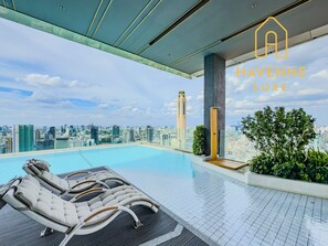 A rooftop infinity pool with lounge chairs, a city skyline view, and the text 'HAVENNE LUXE'.