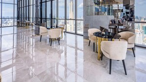 Un amplio y moderno salón con techos altos y grandes ventanales que ofrecen vistas a la ciudad.