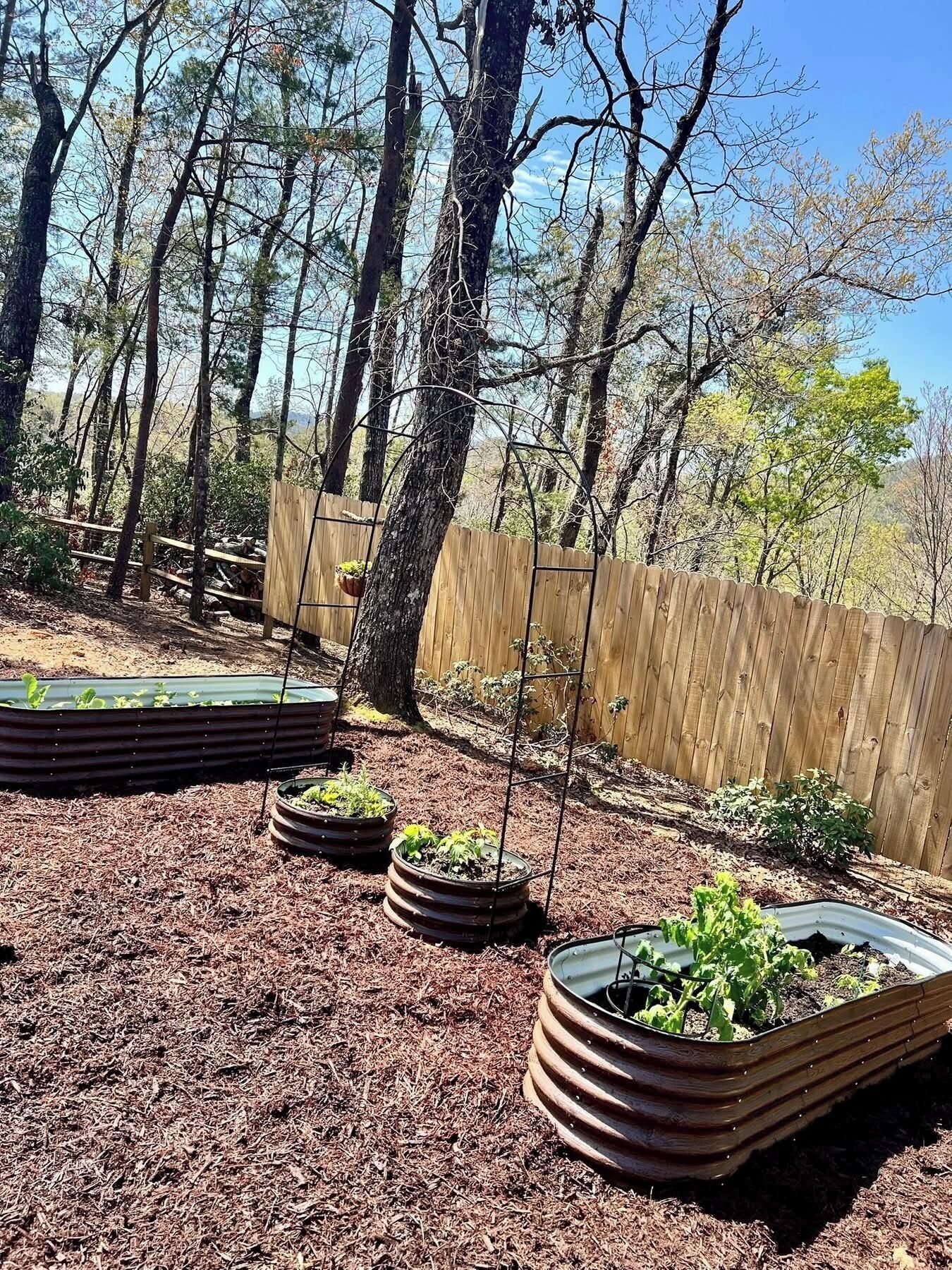 Un giardino con aiuole rialzate e una recinzione in legno.