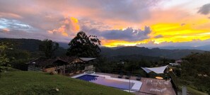 A pool area with lounge chairs and a gazebo, surrounded by lush greenery and hills. - ACAIMA CAFE  (Sasaima)