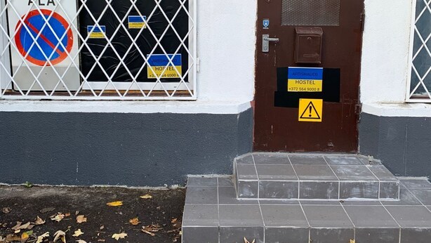 A hostel entrance with a barred window, a no parking sign, and a brown door with a warning sign. - Artishalico tallinn (Tallinn)