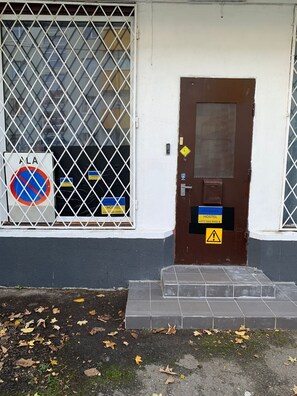 Ein Hostel Eingang mit vergittertem Fenster, einem Verbotsschild und einer braunen Tür mit Warnhinweis.