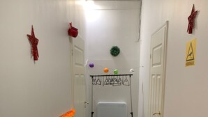 A narrow hallway with white walls, a brown carpet, and a radiator. There are two doors on either side, a red star decoration on the left, and a yellow sign on the right. - Artishalico tallinn (Tallinn)
