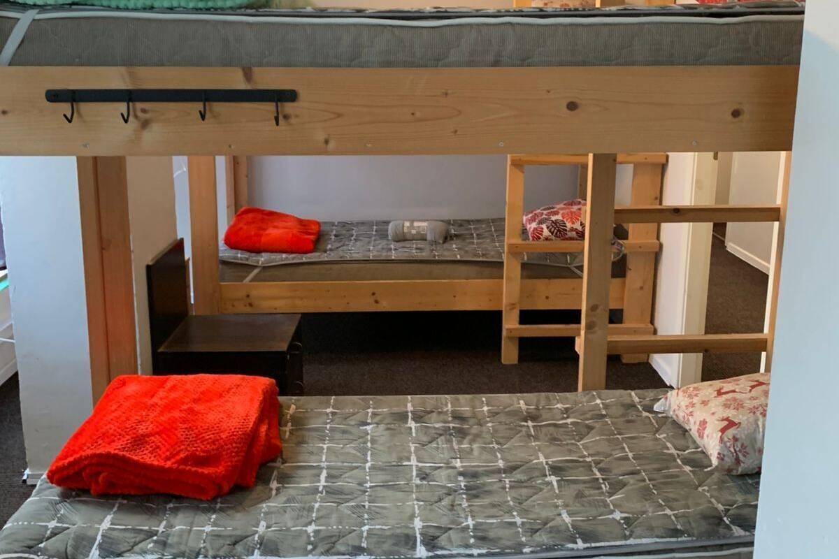 Ein Schlafraum mit Etagenbetten, einem Holzgestell, einem grünen Handtuch und einer roten Decke.