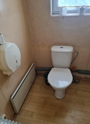 Et lille, enkelt badeværelse med toilet, håndtørrer og radiator.