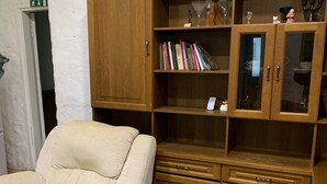 A beige armchair, a wooden bookshelf with glass doors, and a grey trash bin. - Artishalico tallinn (Tallinn)