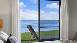 Ein Hotelzimmer mit einer großen Schiebeglasdoor zu einem Rasenbereich mit Blick aufs Meer.