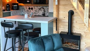 A cozy cabin interior with a kitchen, bar area, and a fireplace. - Cosy escape in a small chalet 🏠 with outdoor jacuzzi! (Eslettes)