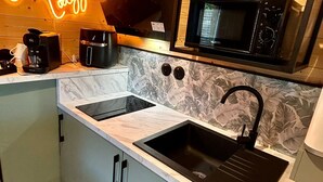 A modern kitchen with a built-in microwave, a coffee maker, and a neon sign. - Cosy escape in a small chalet 🏠 with outdoor jacuzzi! (Eslettes)