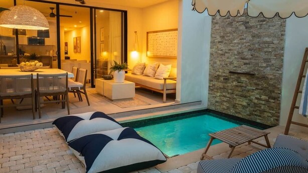 Un área exterior moderna con piscina, una mesa de comedor con sillas, un sofá y una silla de descanso.