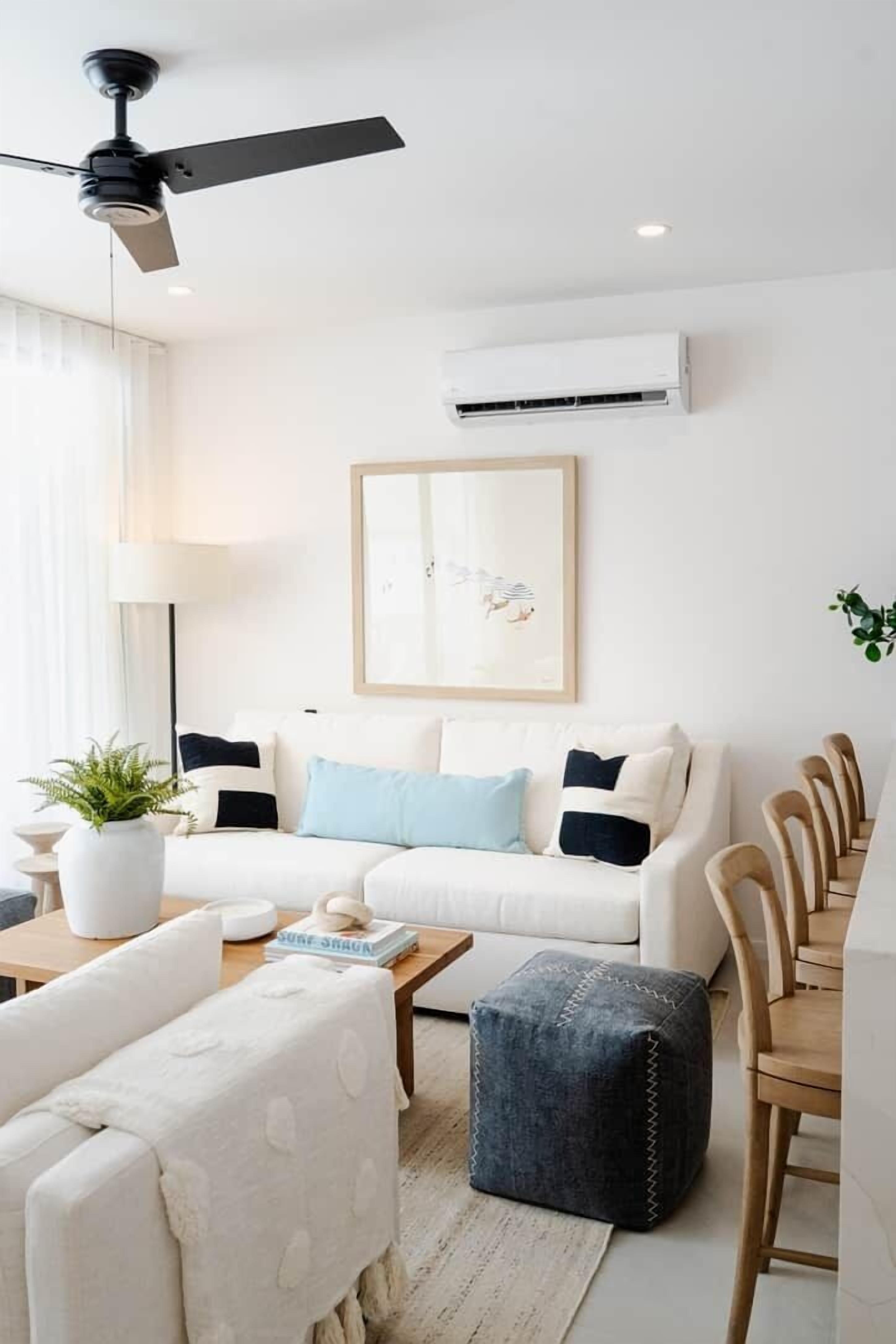 A modern living room with a white sofa, a coffee table, and a ceiling fan.