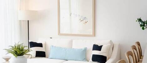 A modern living room with a white sofa, a coffee table, and a ceiling fan.