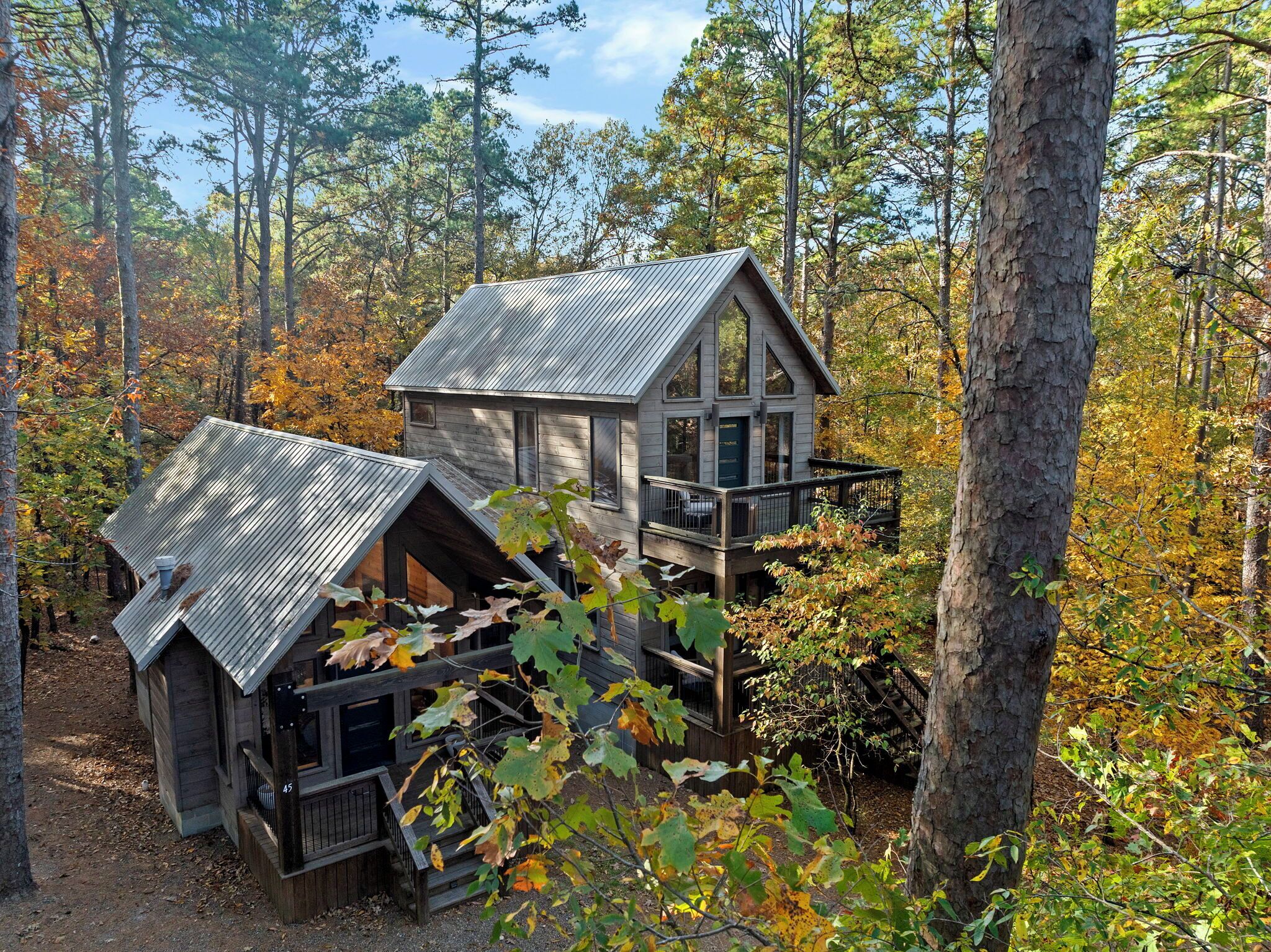 Een chalet met balkon, omringd door bomen en herfstkleuren.