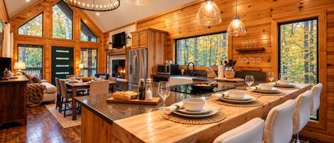 A spacious kitchen with a large island, wooden cabinetry, and a dining area with white chairs.