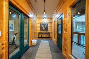 A wooden hallway with glass doors, a treadmill, and a deer painting on the wall.