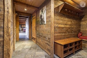 A rustic wooden interior with a bench and shelves, a wooden door, and a hallway leading to another room. - CHALET MONTPERRON - SEEZ (SEEZ)
