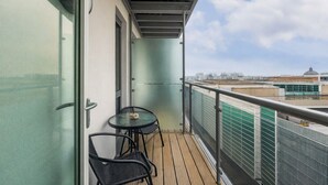 Un balcone con una porta vetrata, due sedie e un tavolo.