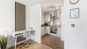 Una cucina moderna con mobili bianchi, elettrodomestici in acciaio inossidabile e una parete d'accento in legno.