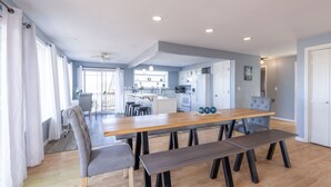 Una cucina moderna con mobili bianchi, un piano di lavoro in legno e un'area pranzo con tavolo e panche.