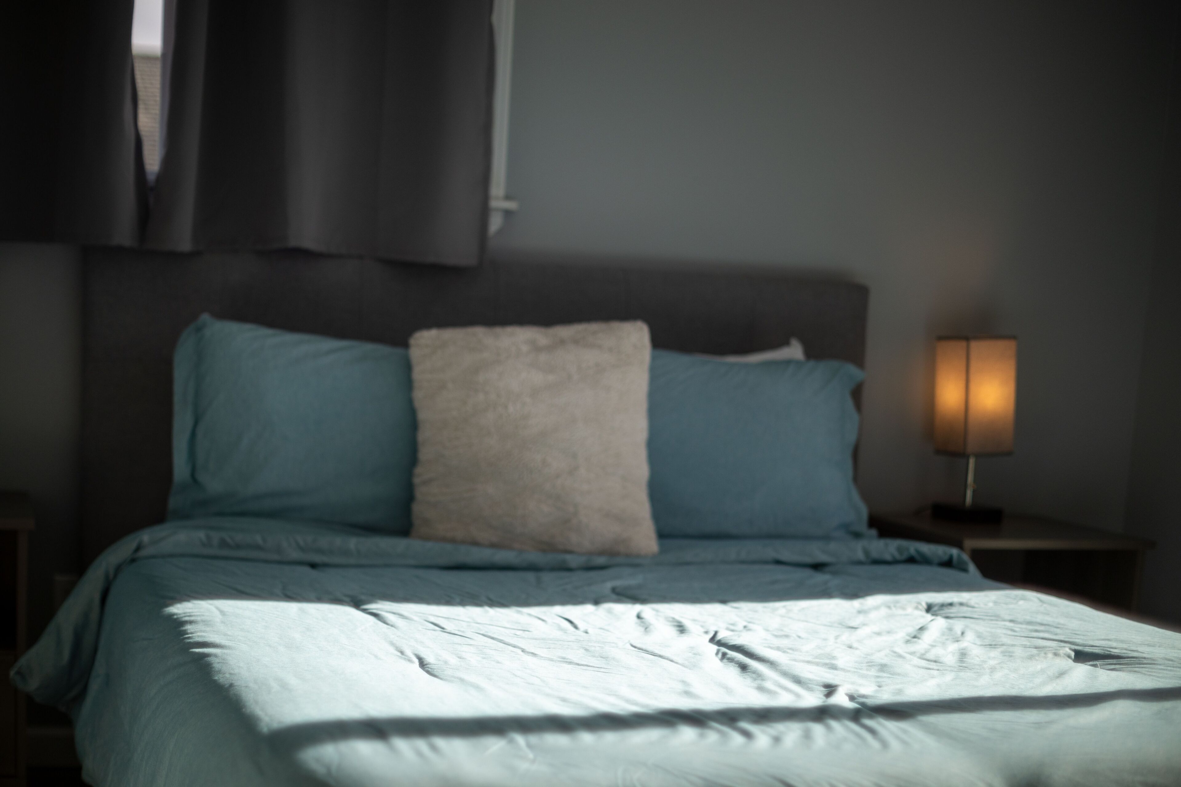 Une chambre à coucher avec un lit, des oreillers, une lampe de chevet et une table de chevet.