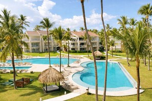 A resort with a large pool, palm trees, and a building with multiple balconies.