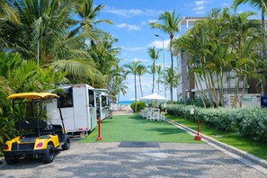 Une rue où se trouve un camion-restaurant, un immeuble avec vue sur la plage et une pelouse verdoyante.