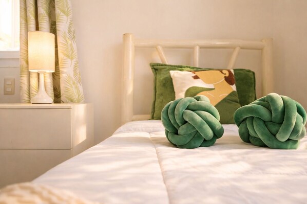 A bed with a white headboard, a green pillow, and a green decorative item on the bed.