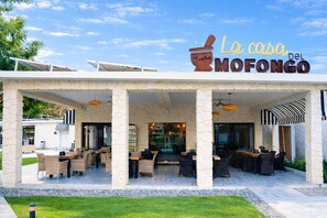 An outdoor seating area with stone pillars and wicker furniture at La casa del Mofongo.