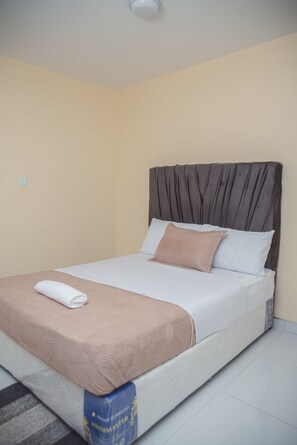 Un lit simple avec une tête de lit, une couverture et un oreiller.