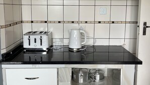 A kitchen with white cabinets, a black countertop, a toaster, a coffee maker, and a stainless steel sink.