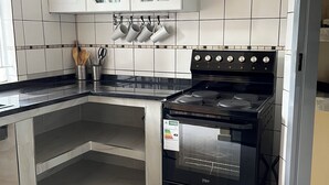 A kitchen with white cabinets, a black stove, and a tiled backsplash.