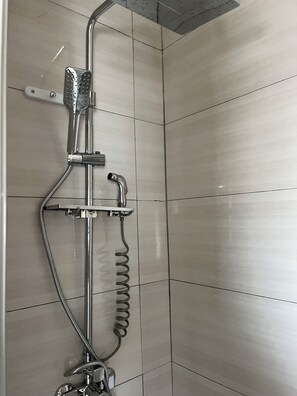 Une douche équipée d’un pommeau de douche à main et d’un flexible.