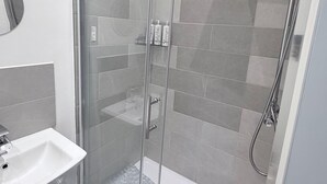 A modern bathroom with a glass-enclosed shower, a white sink, and a mirror. - Apartment 2- 216 High Street (Arbroath)