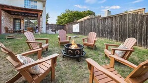A backyard with a fire pit, wooden chairs, and a patio area. - 4BR Frisco Retreat Near Universal Kids Resort & Toyota + BBQ & Firepit (Frisco)