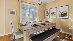 A dining area with a wooden table set for four, a bench, and a window with blinds. - 4BR Frisco Retreat Near Universal Kids Resort & Toyota + BBQ & Firepit (Frisco)