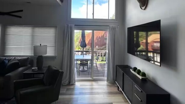 A modern living room with a large TV, a sofa, a coffee table, and a fireplace.